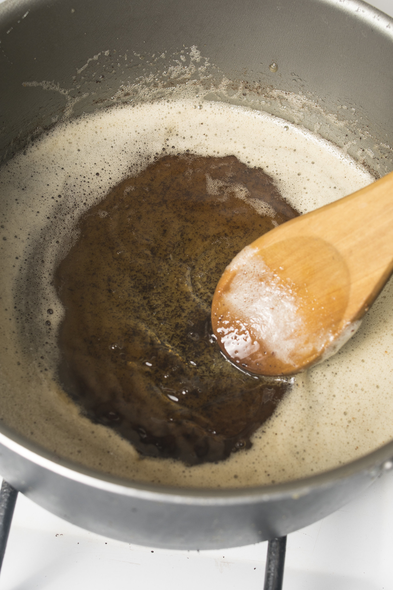 Browned butter in a saucepan with deep golden toasted milk solids and foam around the edges.